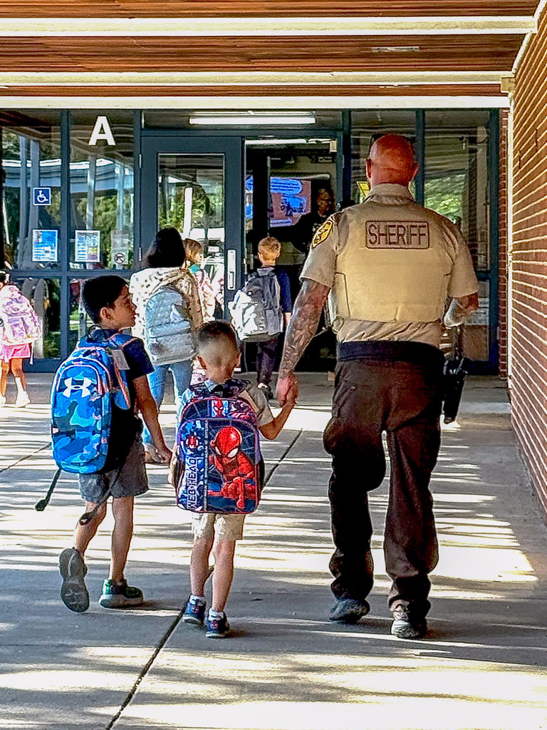 will County Sheriff deputy holds hands and walks with kindergartner into school
