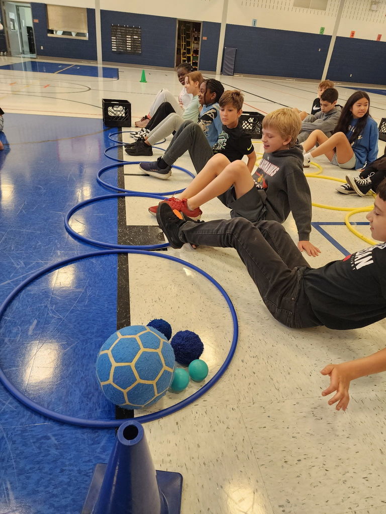 Students sitting in the gym with their knees up
