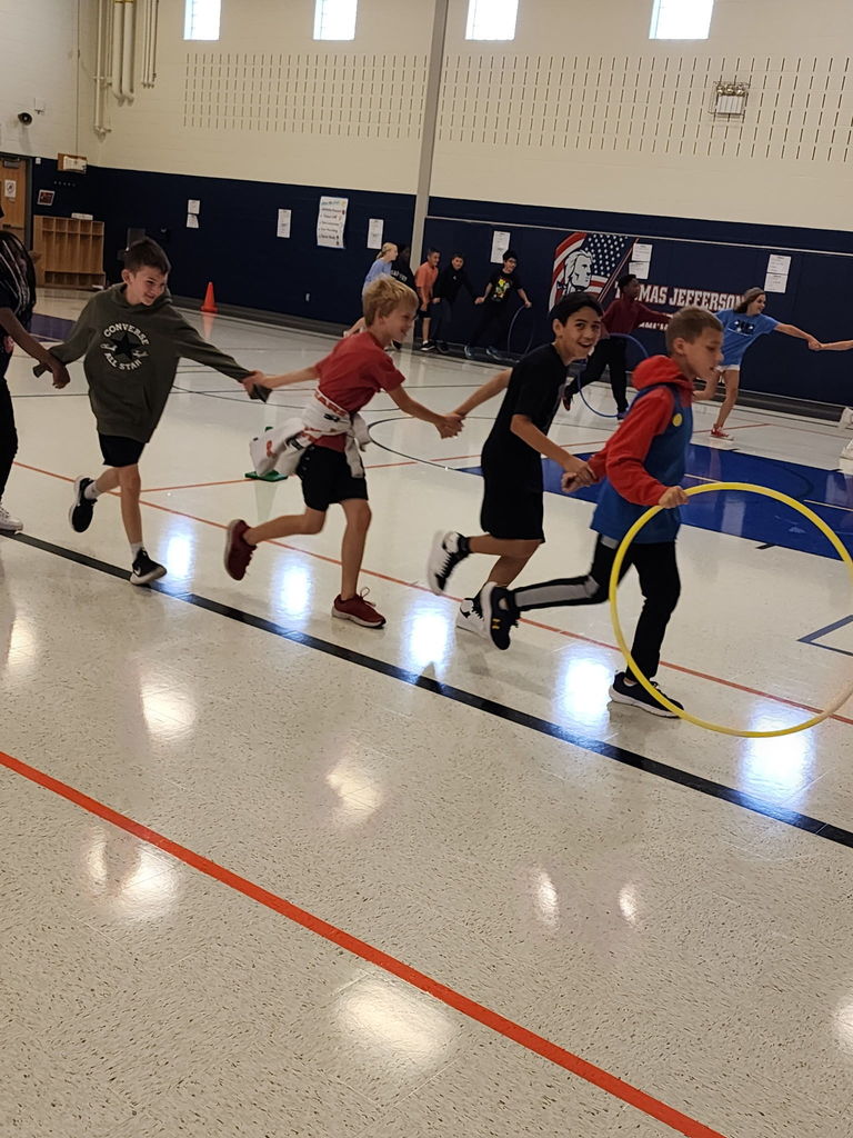 Students running in a gym holding hands .