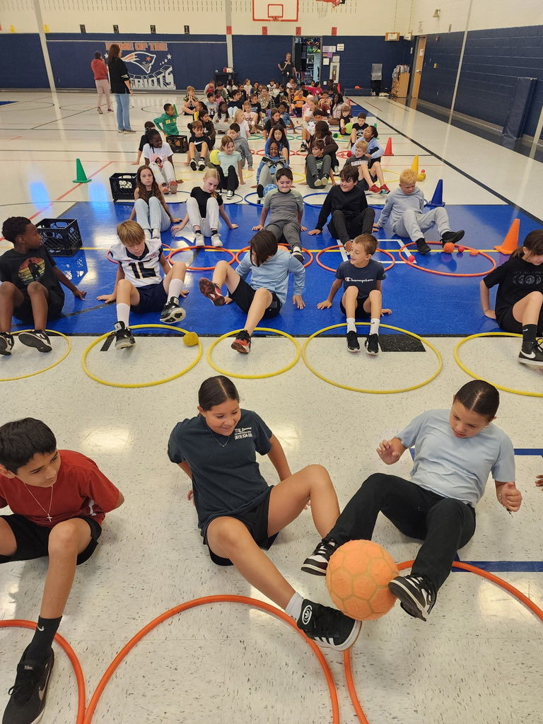 Students in a gym passing a ball to each other using your feet