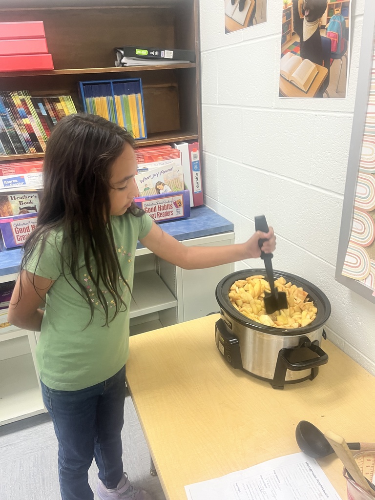 A student is stirring applesauce in a crockpot. 