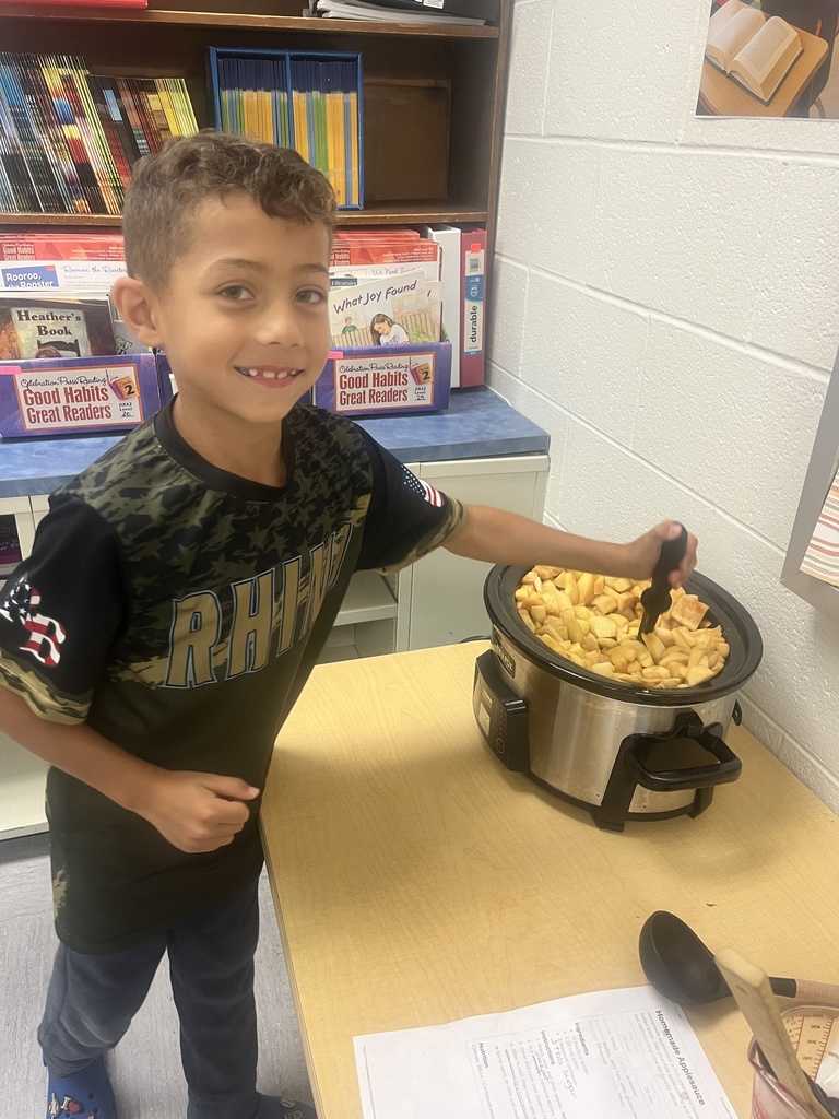 A student is stirring applesauce in a crockpot. 