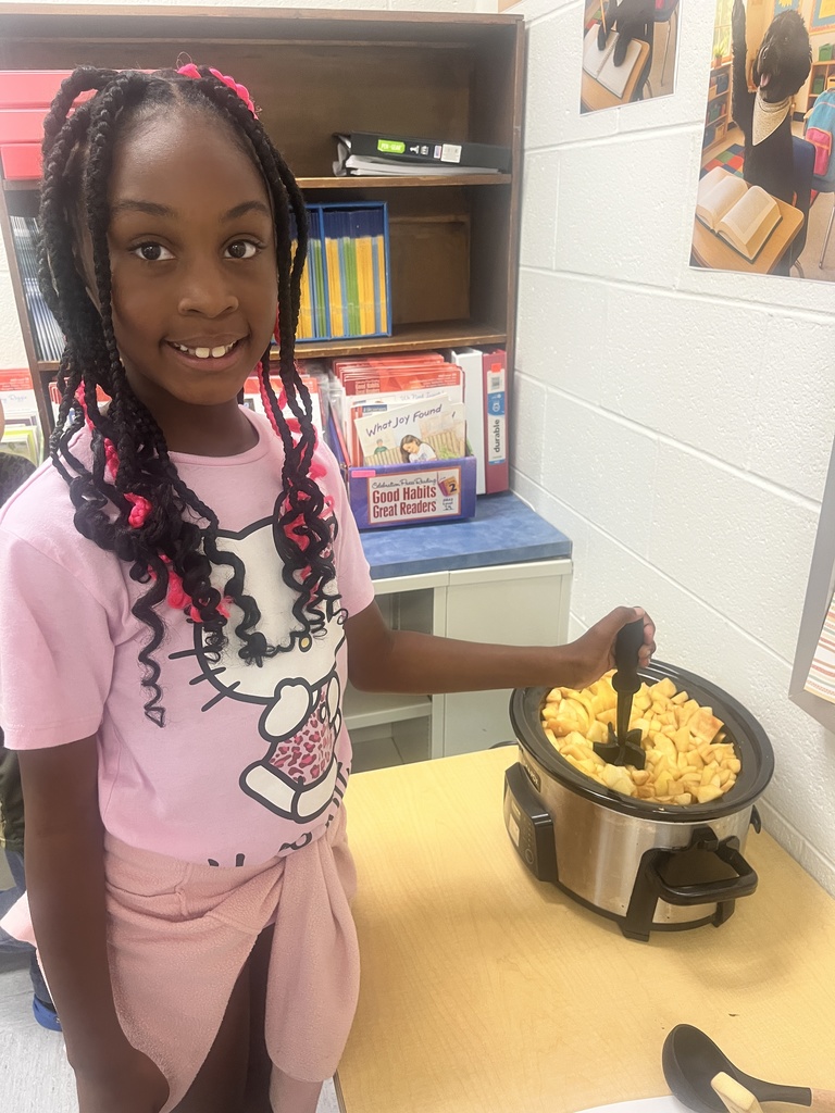 A student is stirring applesauce in a crockpot. 