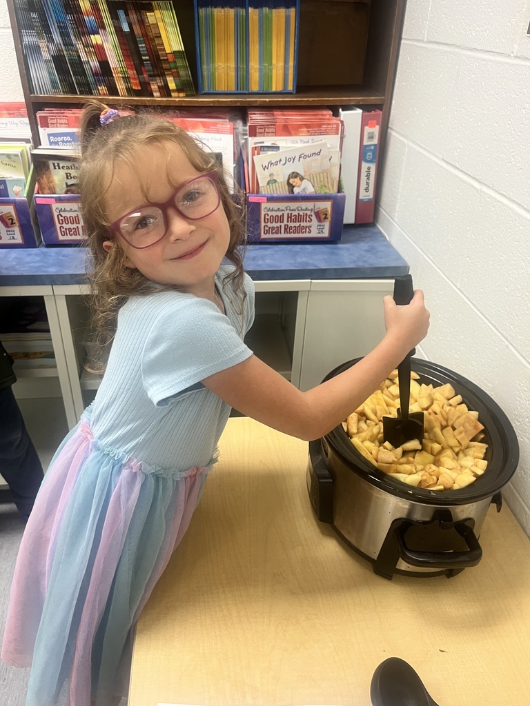 A student is stirring applesauce in a crockpot. 