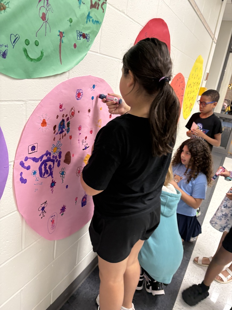 Students are drawing on a circular shaped paper in a hallway. 