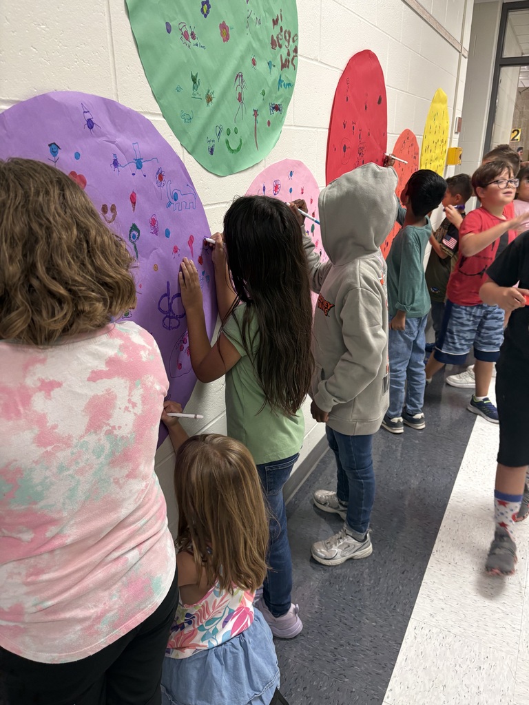 students are drawing on a circular shaped paper in a hallway. 