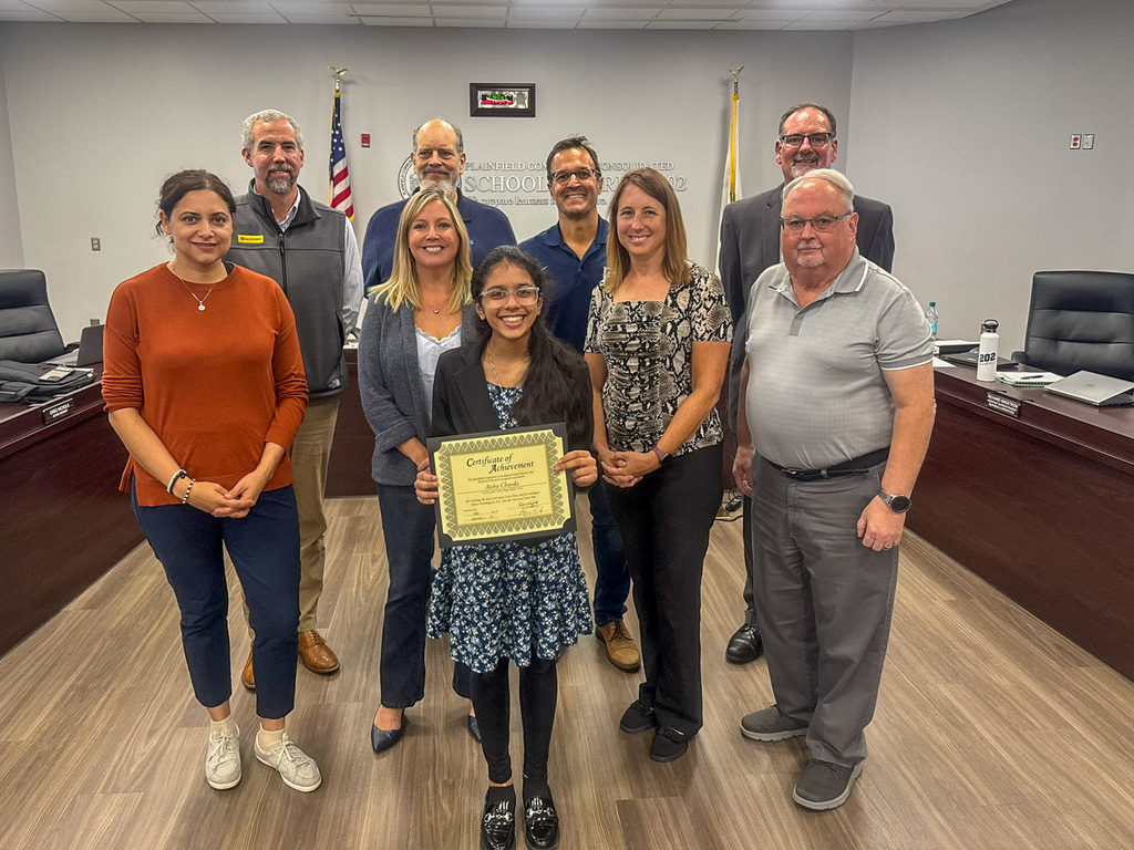 eight adults stand around a student holding a certificate