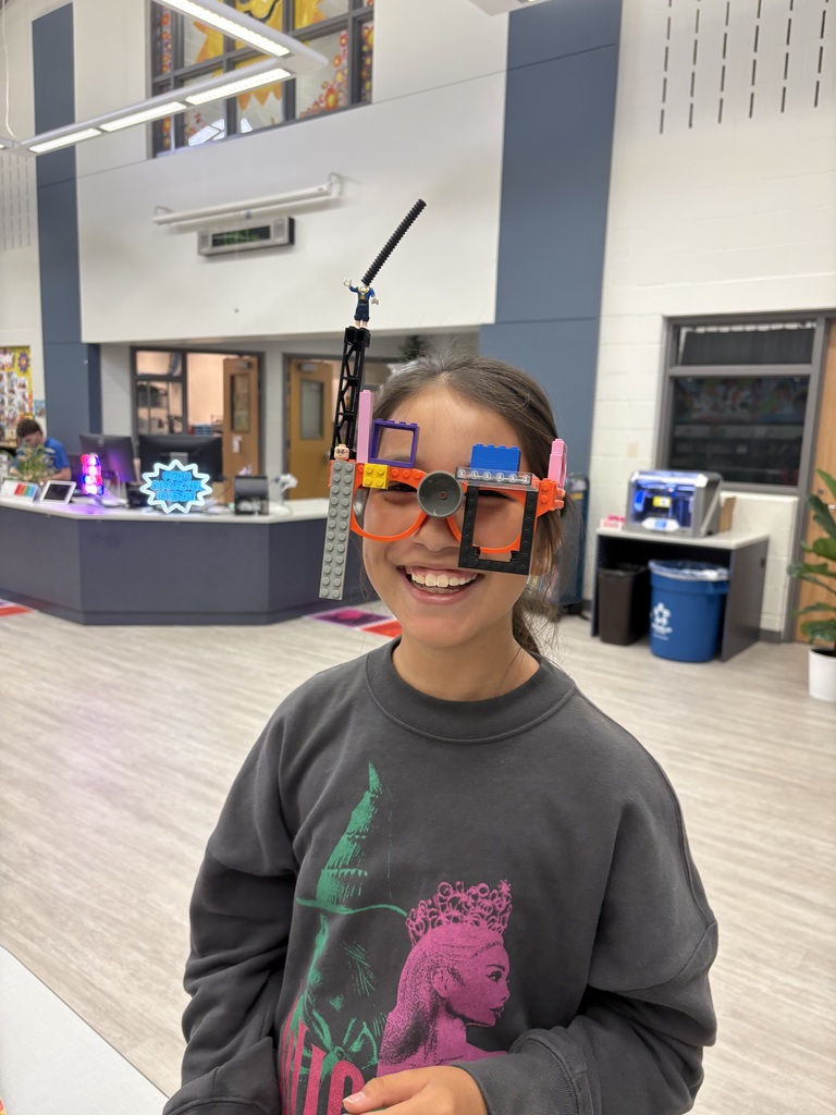A student standing in the library wearing Lego glasses. 