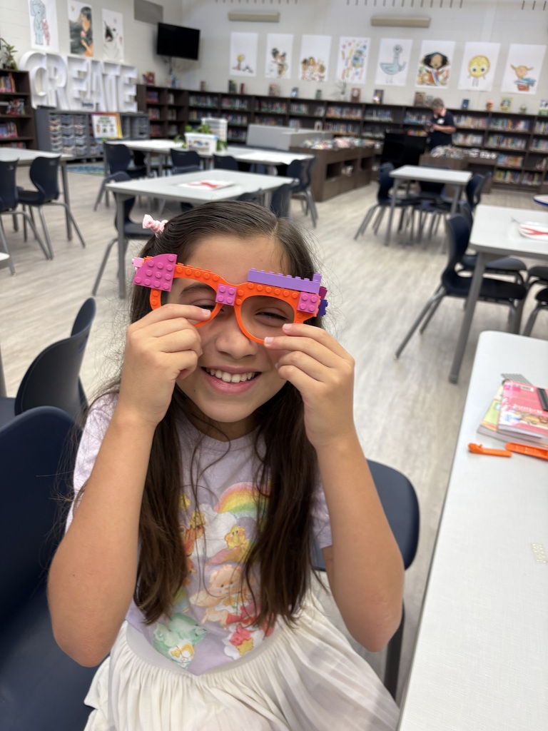 A student standing in the library wearing Lego glasses. 