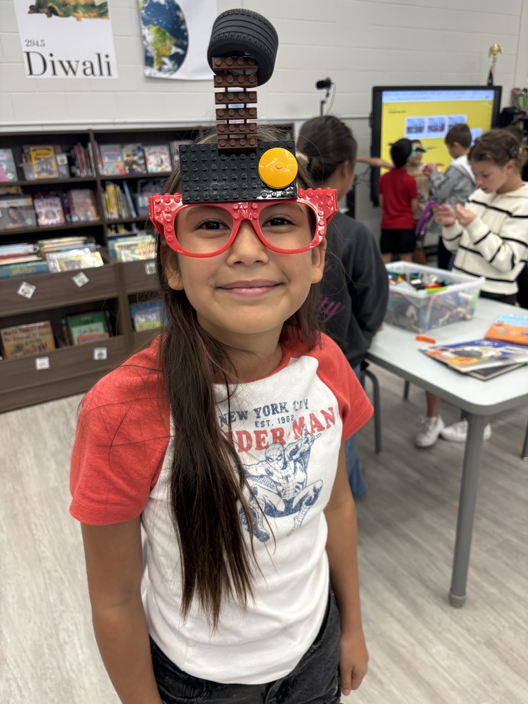 A student standing in the library wearing Lego glasses. 
