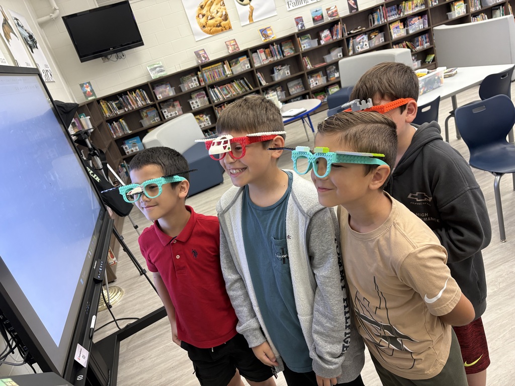 Four students standing in the library wearing Lego glasses. 