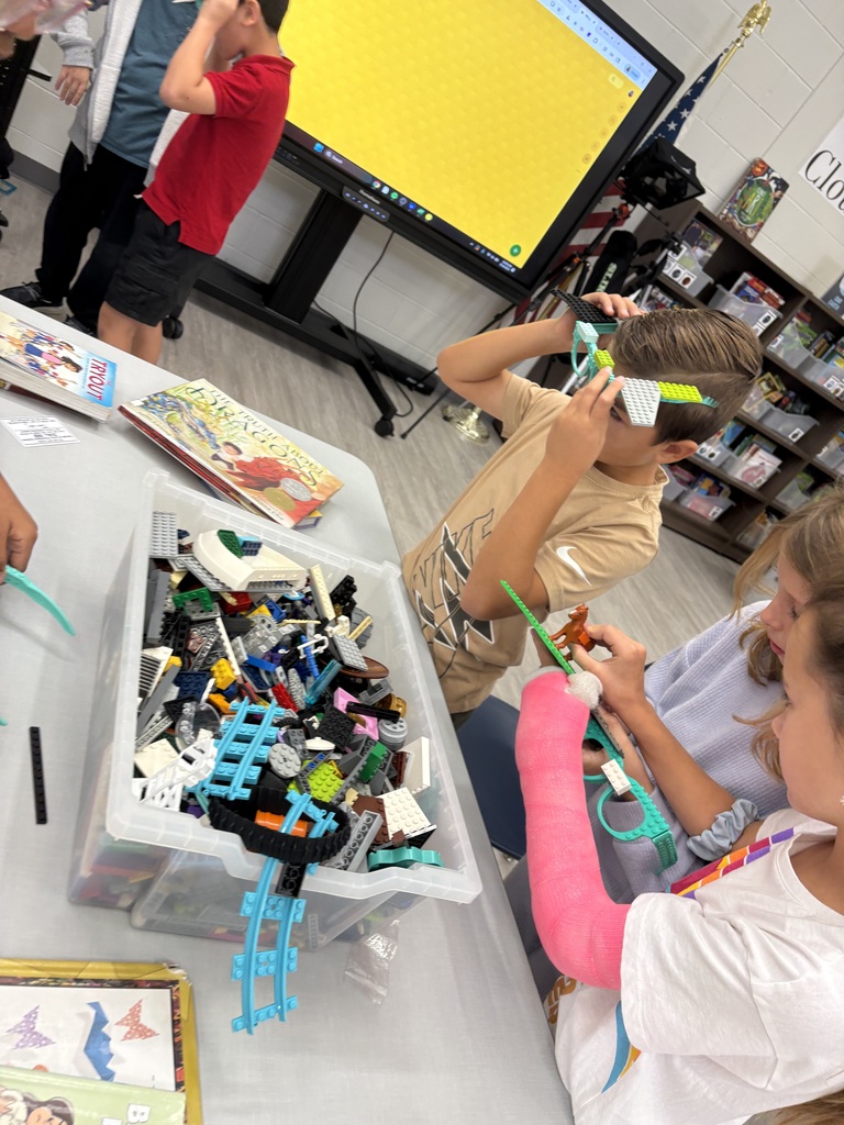 Three students building with Legos in the library. 