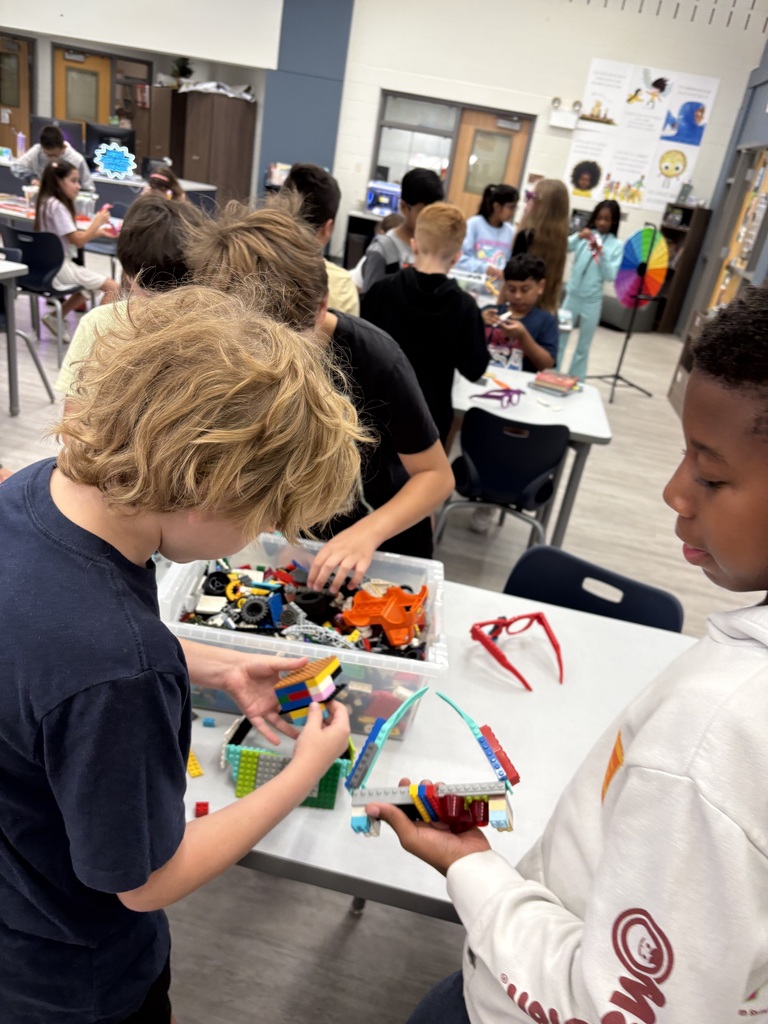 Three students building with Legos in the library. 