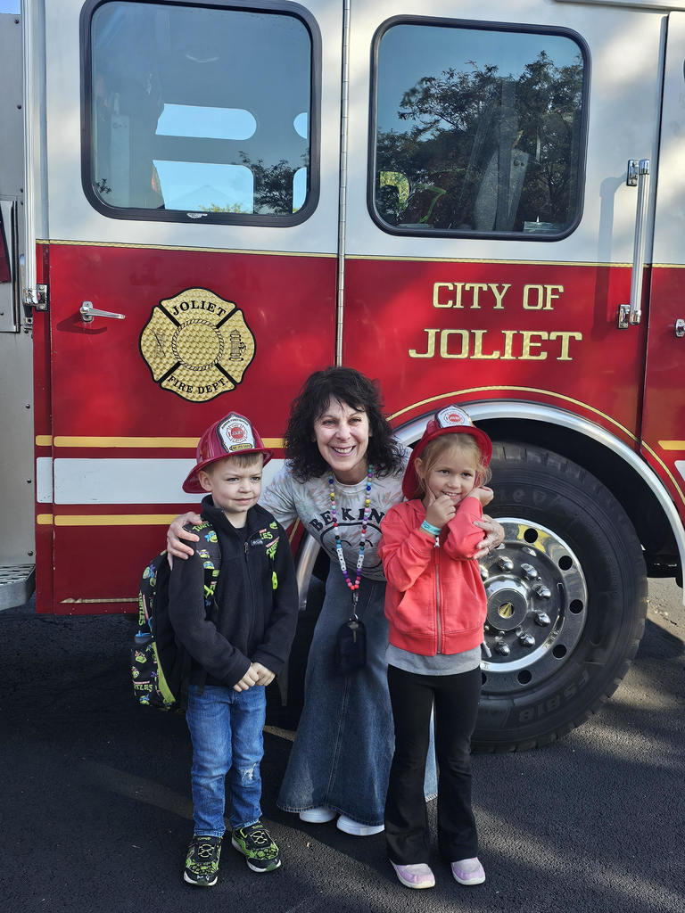 two students and teacher stand in front of red Joliet Fire Department fire truck