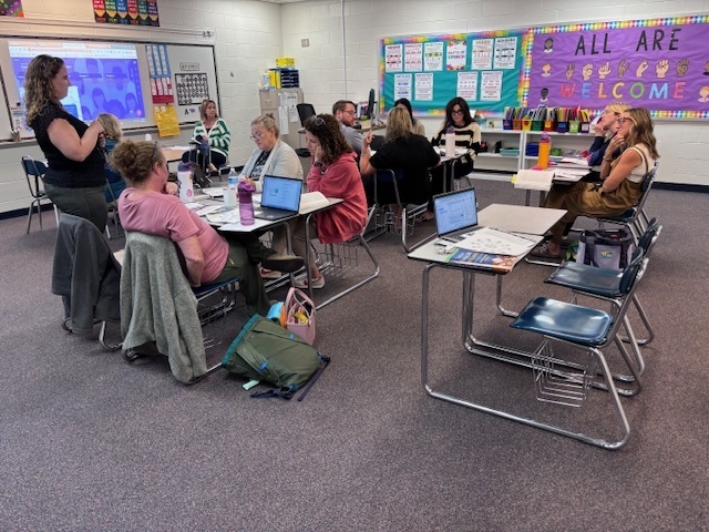 Group of teachers sit in classroom talking