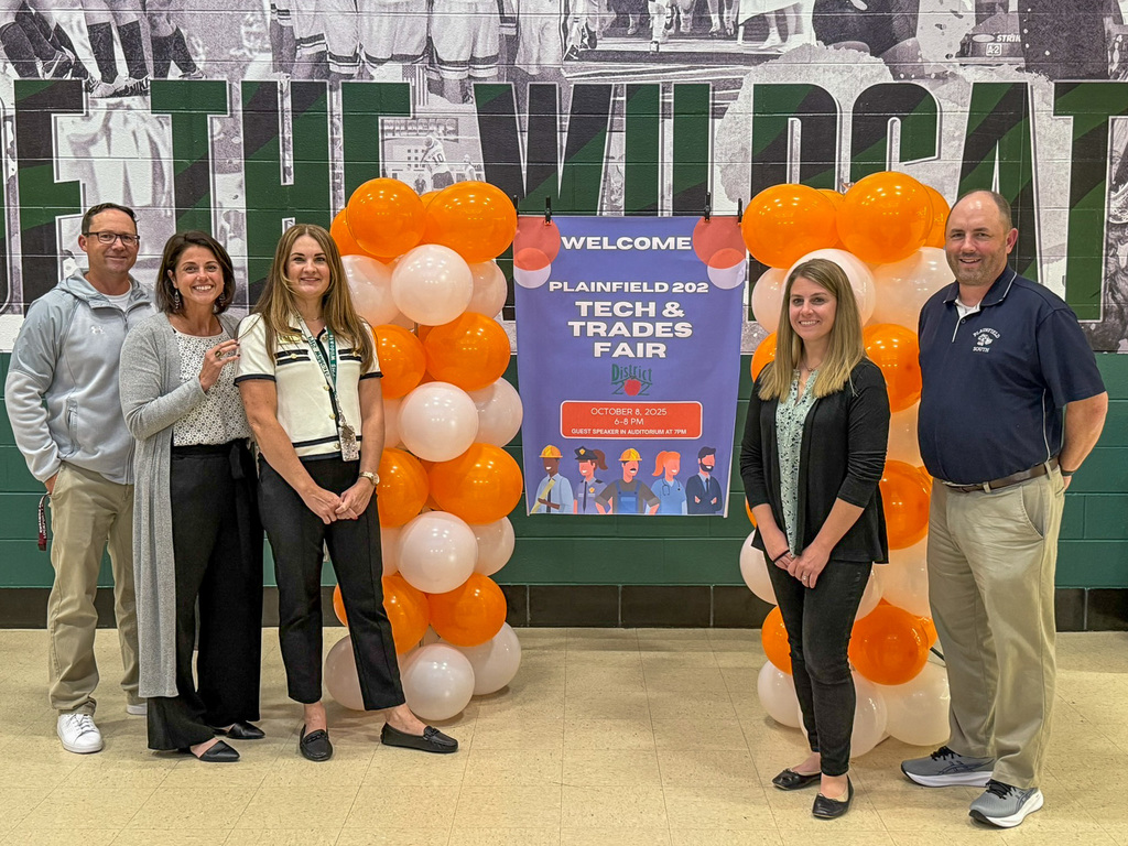 five adults stand with oranges and white balloons