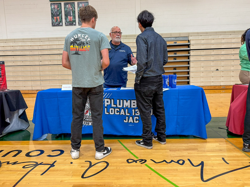 two students stand around employer table in gym