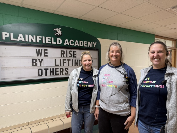 three adults stand in school hallway