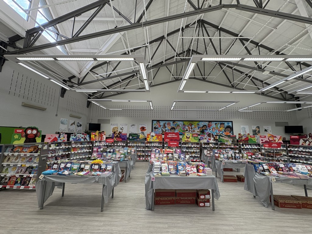 Books are displayed on tables in a library.