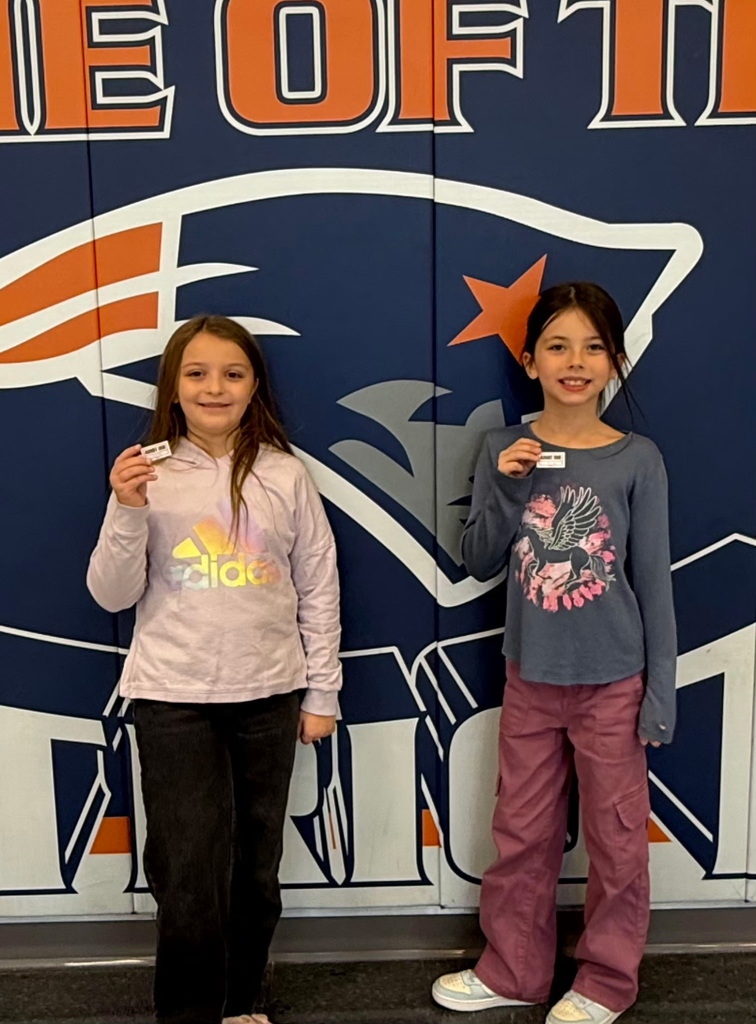 Two students standing in a hallway in a school holding a raffle ticket.
