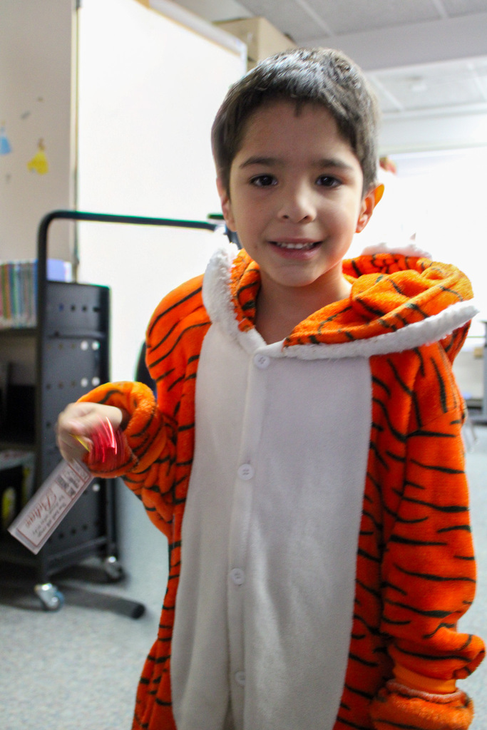student dressed in tiger onesie holds bell