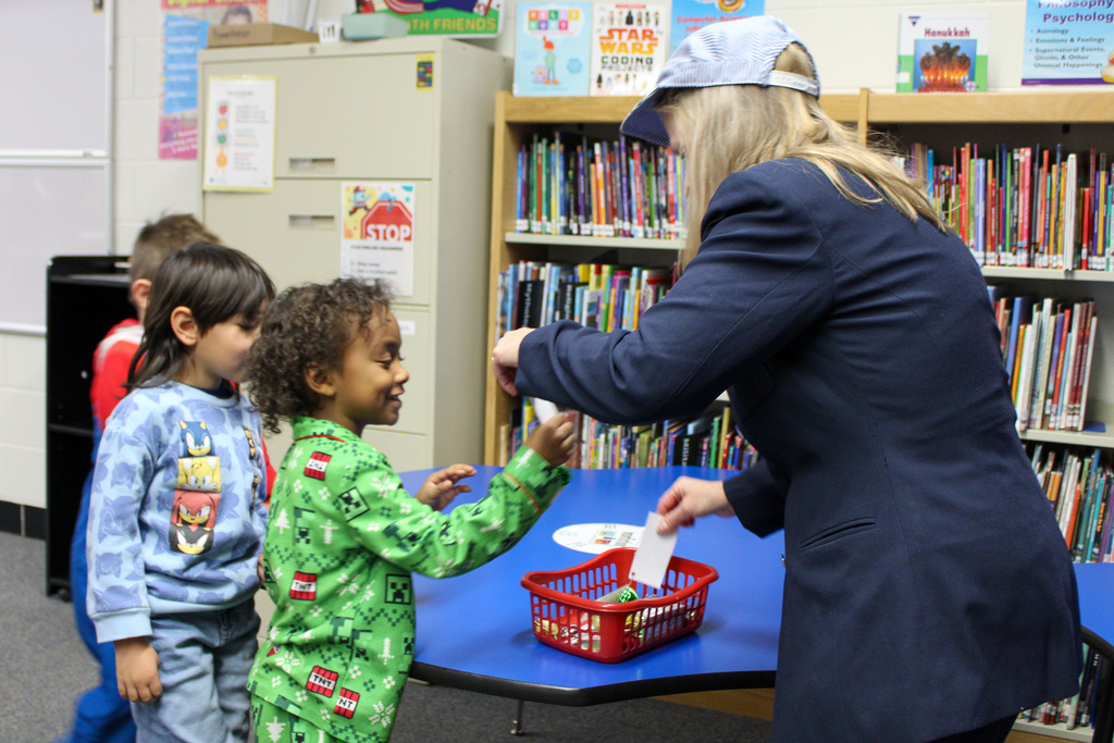 adults dressed as a train conductor hands student bell