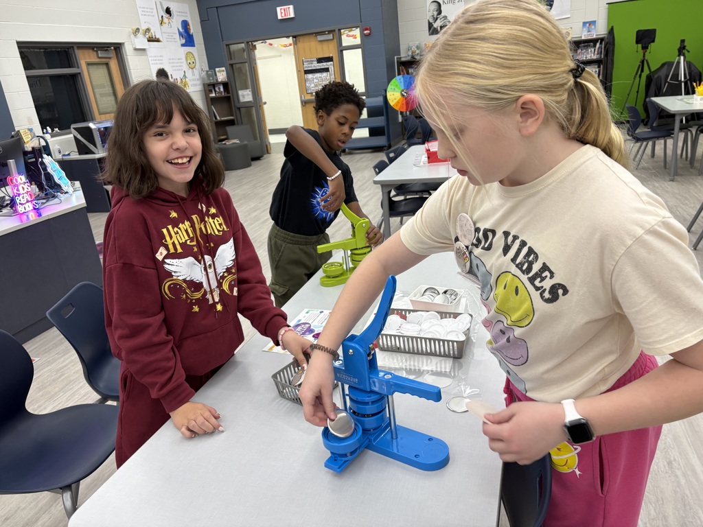 Students making buttons in a library.