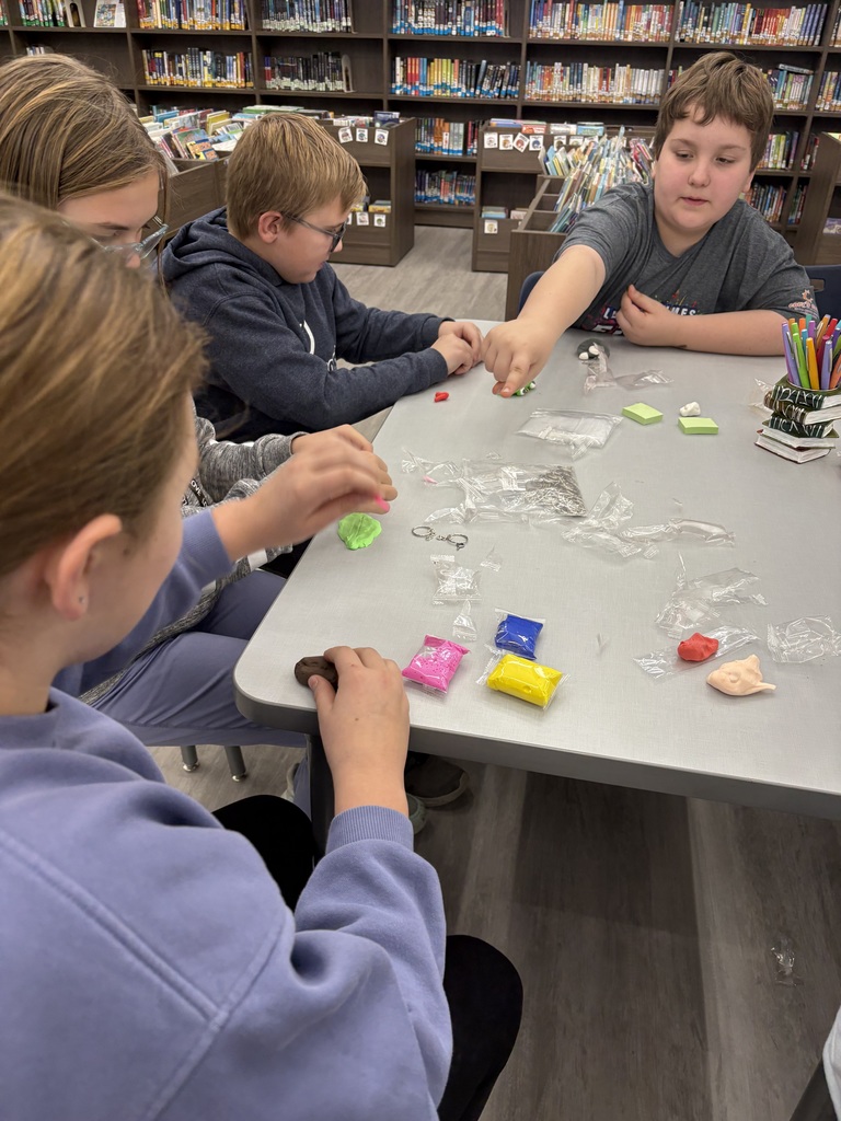 Students making clay objects in a library.
