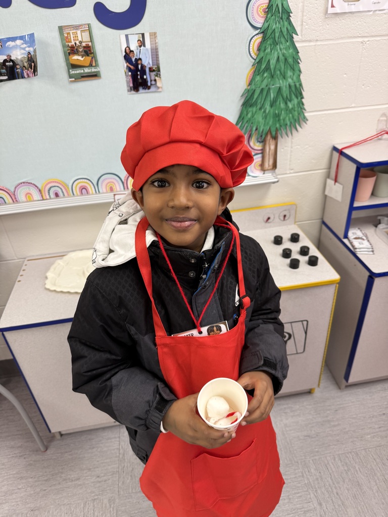 A student wearing a red apron and chef hat. 
