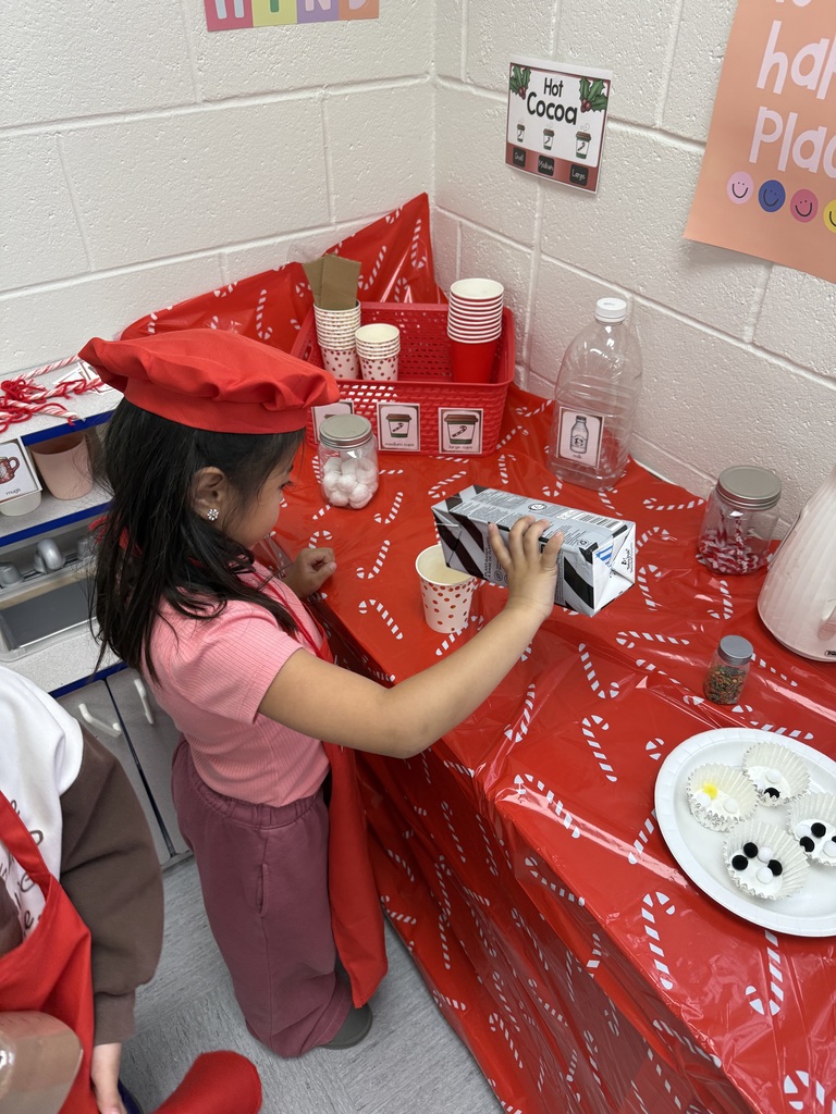 A student pretends to pour milk into a cup. 