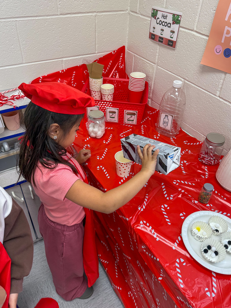 kindergarten student pours milk in cup