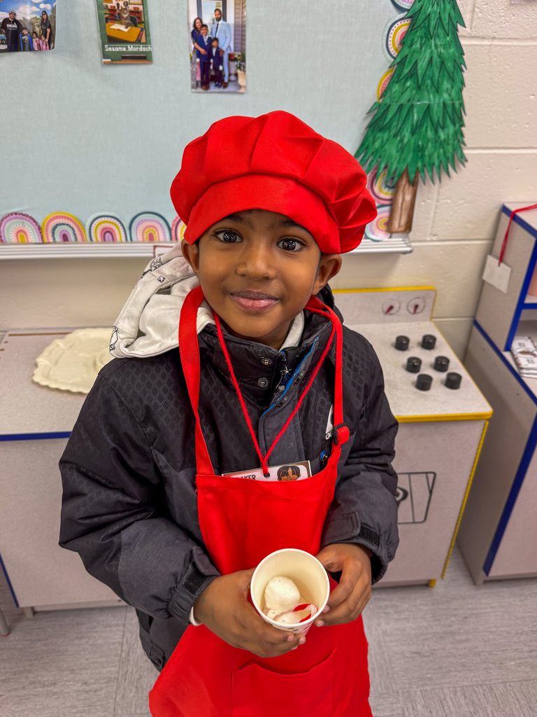 kindergarten student holds cup dressed as a chef