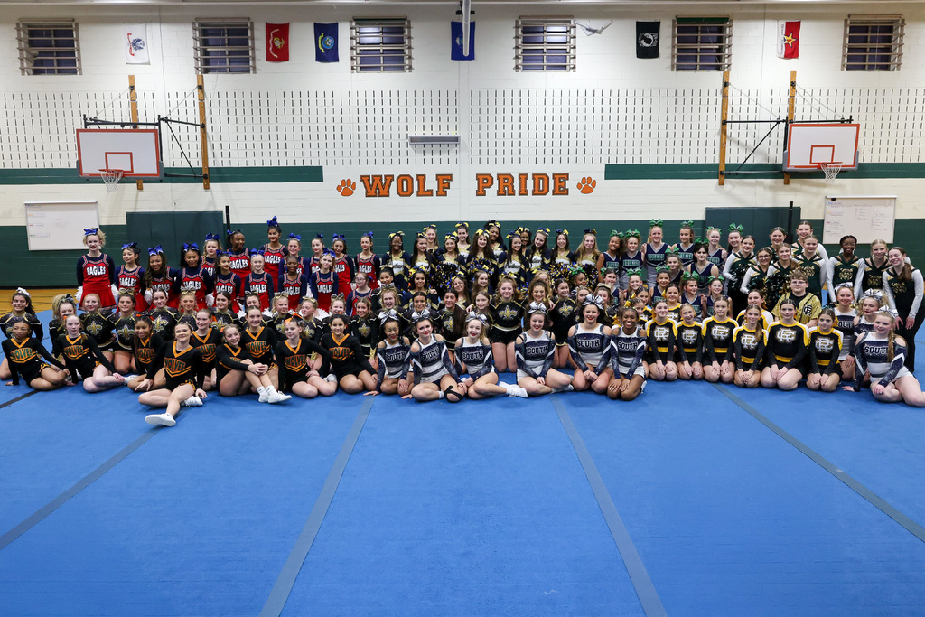 group of middle school cheerleaders pose on gym mats 
