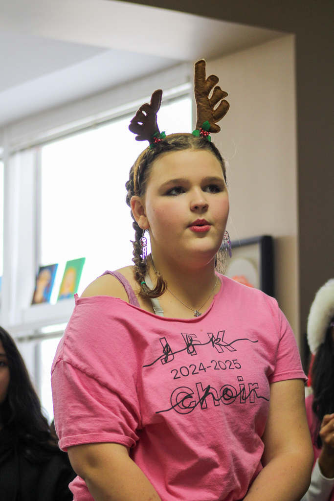 girl in pink shirt wearing reindeer antlers sings