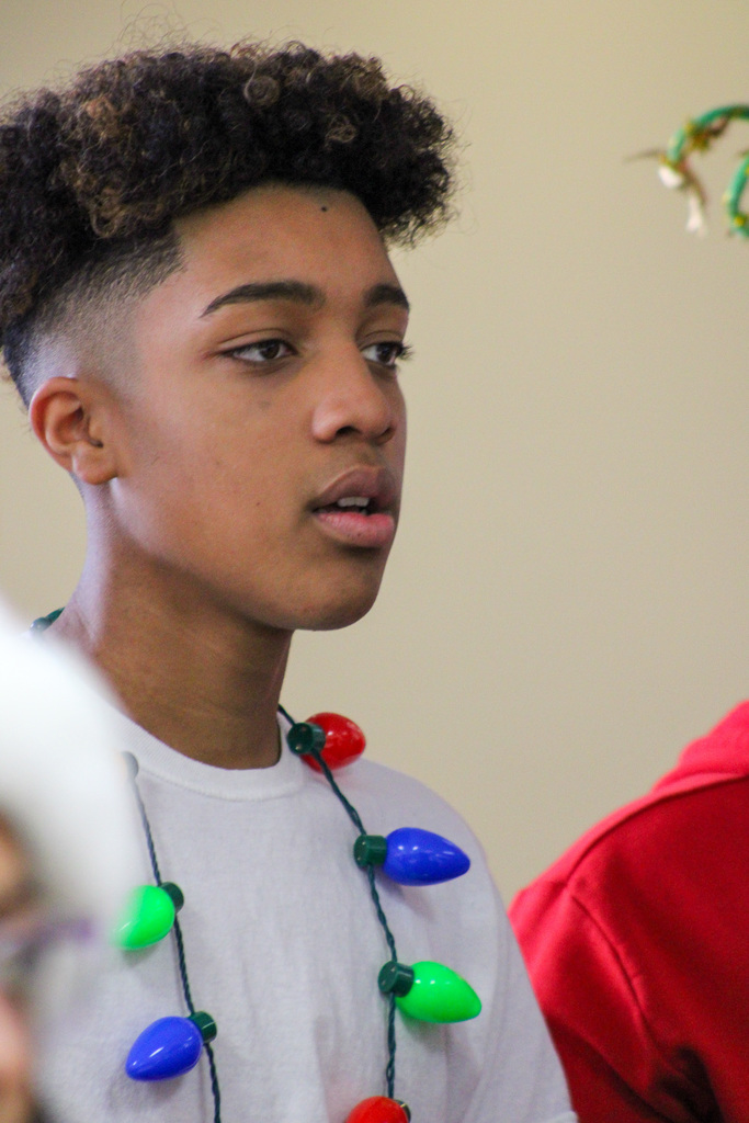 middle school student wearing Christmas light necklace sings