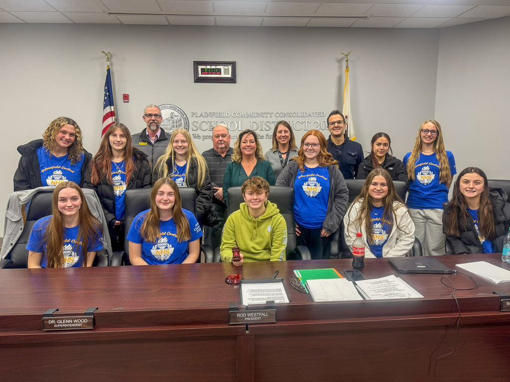 group of student sitting at table posing with Board of Education members behind them