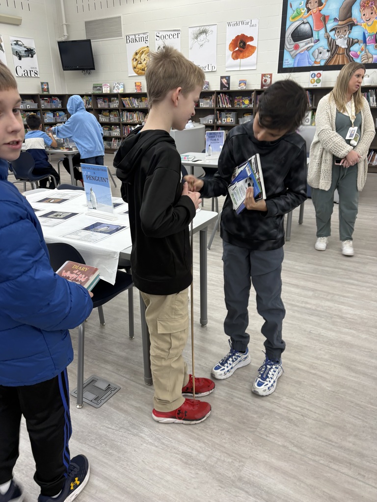 Two students using a meter stick in the library. 