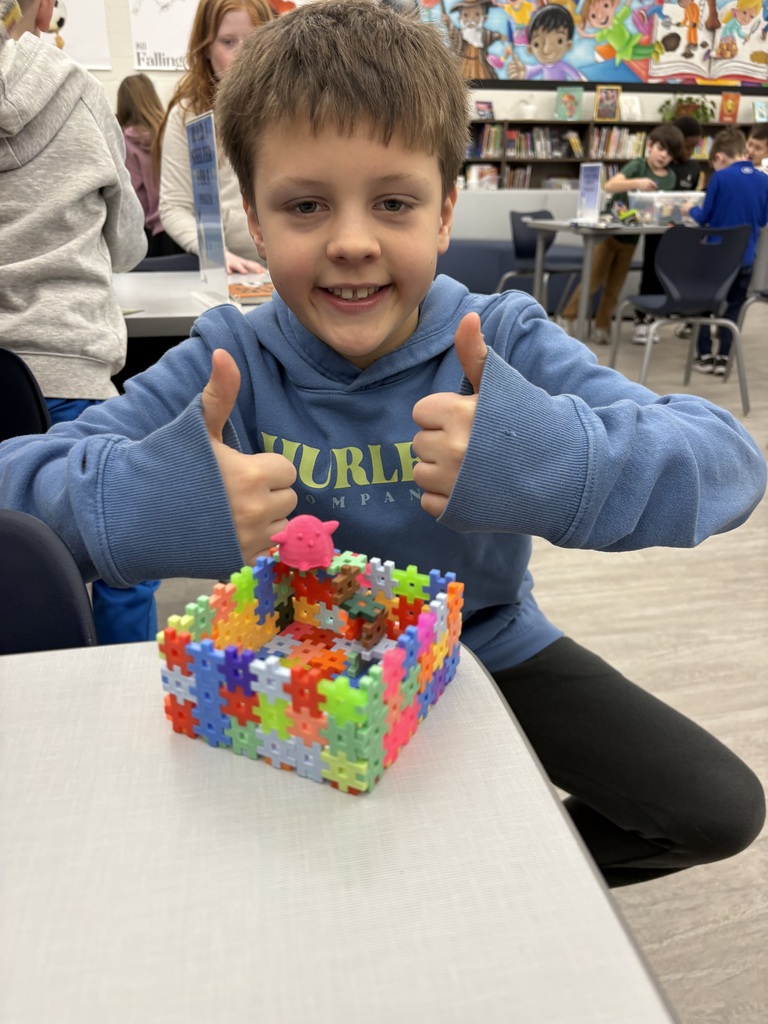 A student is showing a small structure he built in the library. 