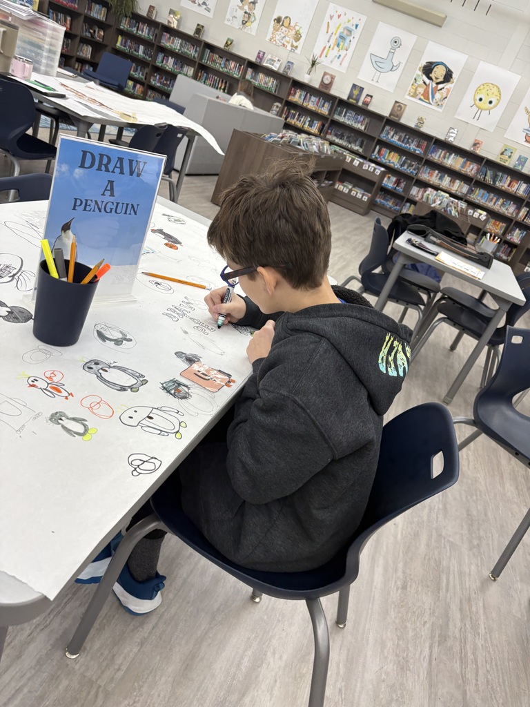 A student drawing a penguin in a library. 