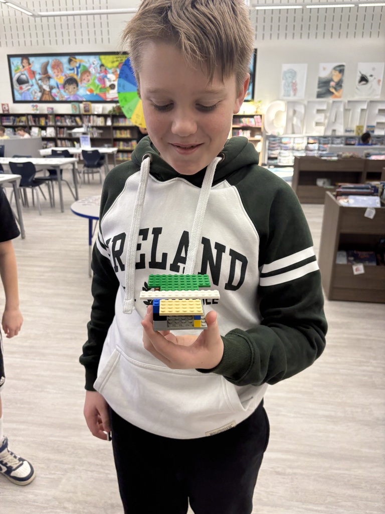 A student is showing a small structure he built in the library. 