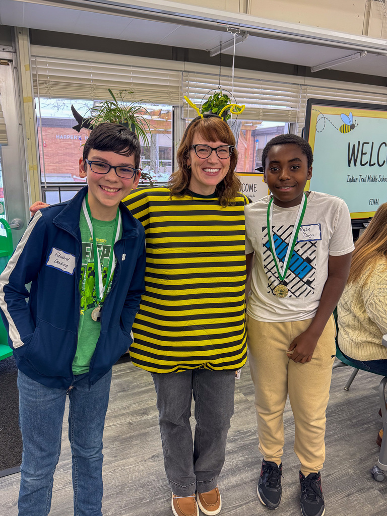 woman dressed as a bee stands between the top two winners at the spelling bee