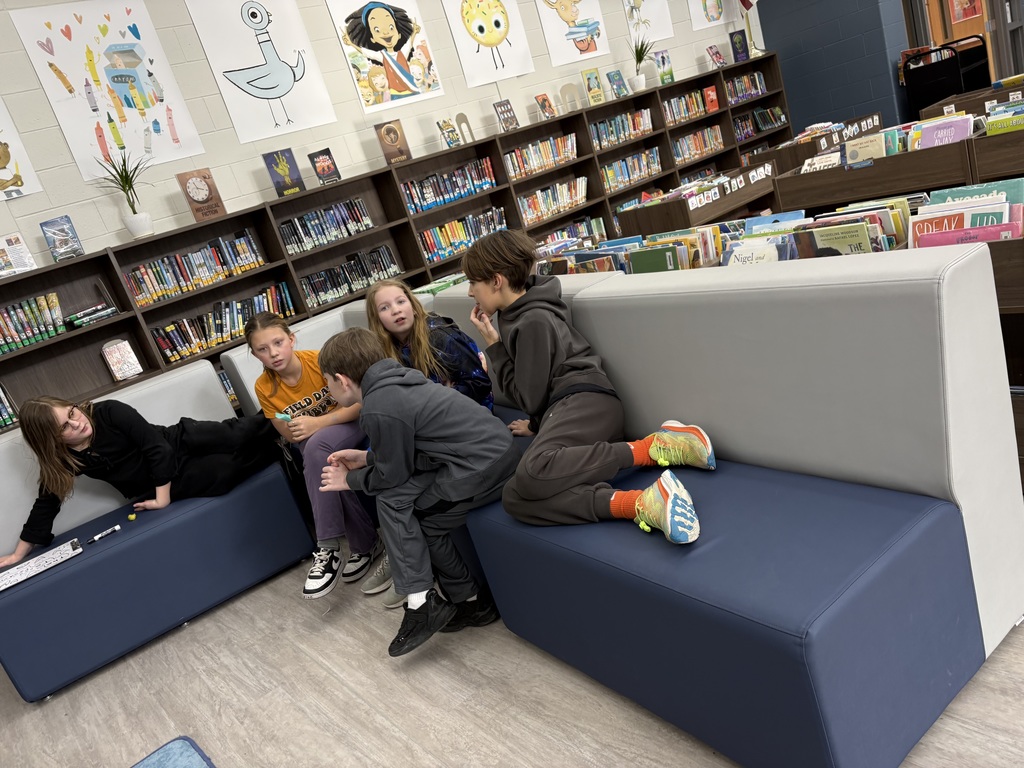 Students are sitting on a couch in the library. 