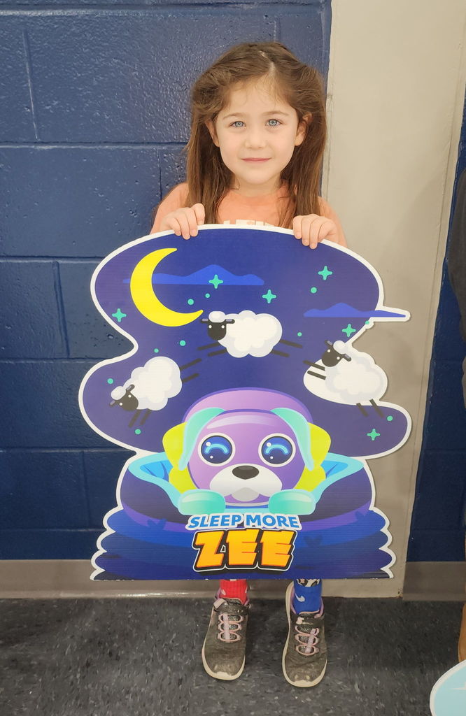 Student standing in front of cardboard, cut outs in a school gym