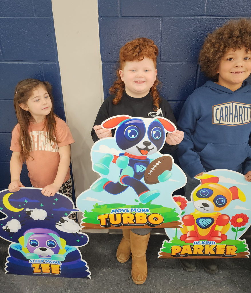 Students  standing in front of cardboard, cut outs in a school gym
