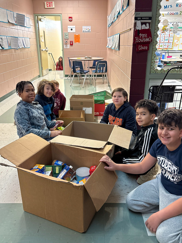 Students sit on floor packing food into boxes