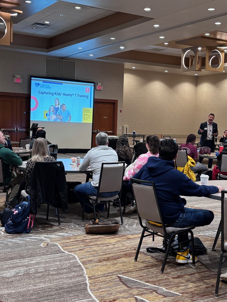 groups of people sit at table looking at screen