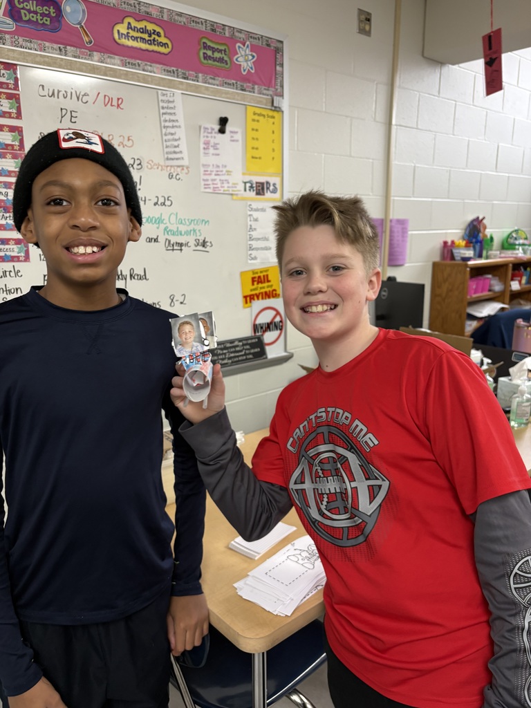 Two students holding a paper bobsleigh. 