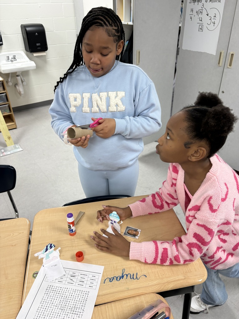 Two students creating a paper bob sled. 