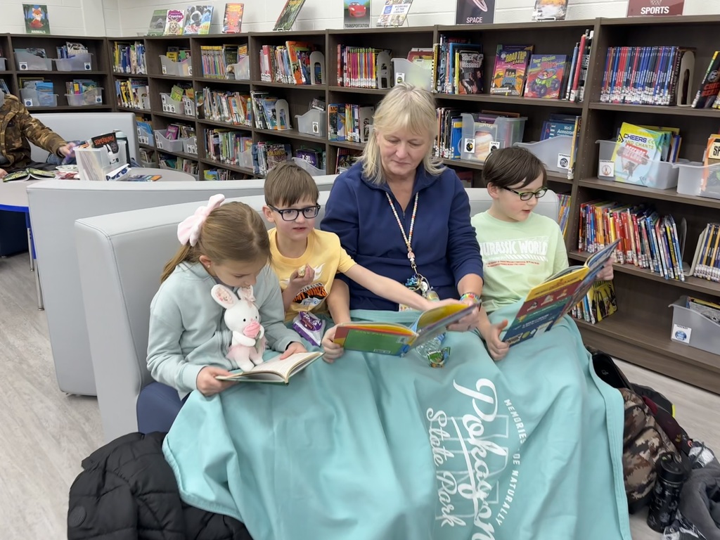 A grandma and her grandchildren sitting on a couch in a library reading