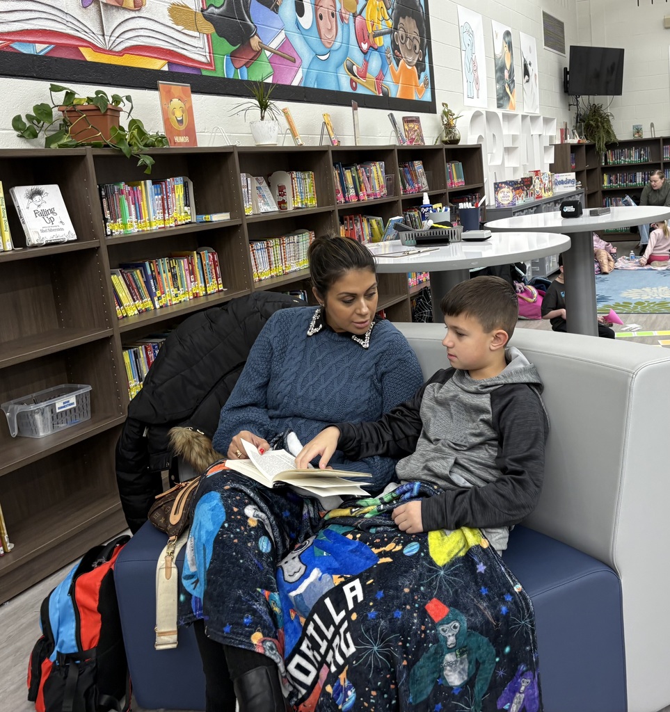 A mom and son sitting in a library on a couch reading
